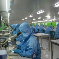 Staff in protective clothing working with microscopes in a cleanroom
