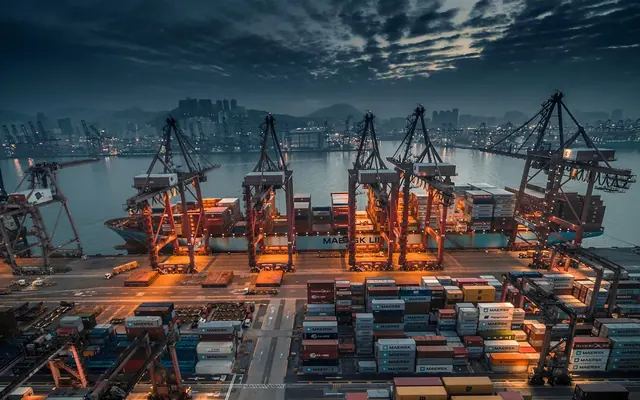 Port cranes loading a container ship at dusk