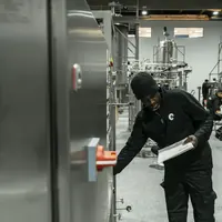 An auditor holding documents inspects equipment in a production facility