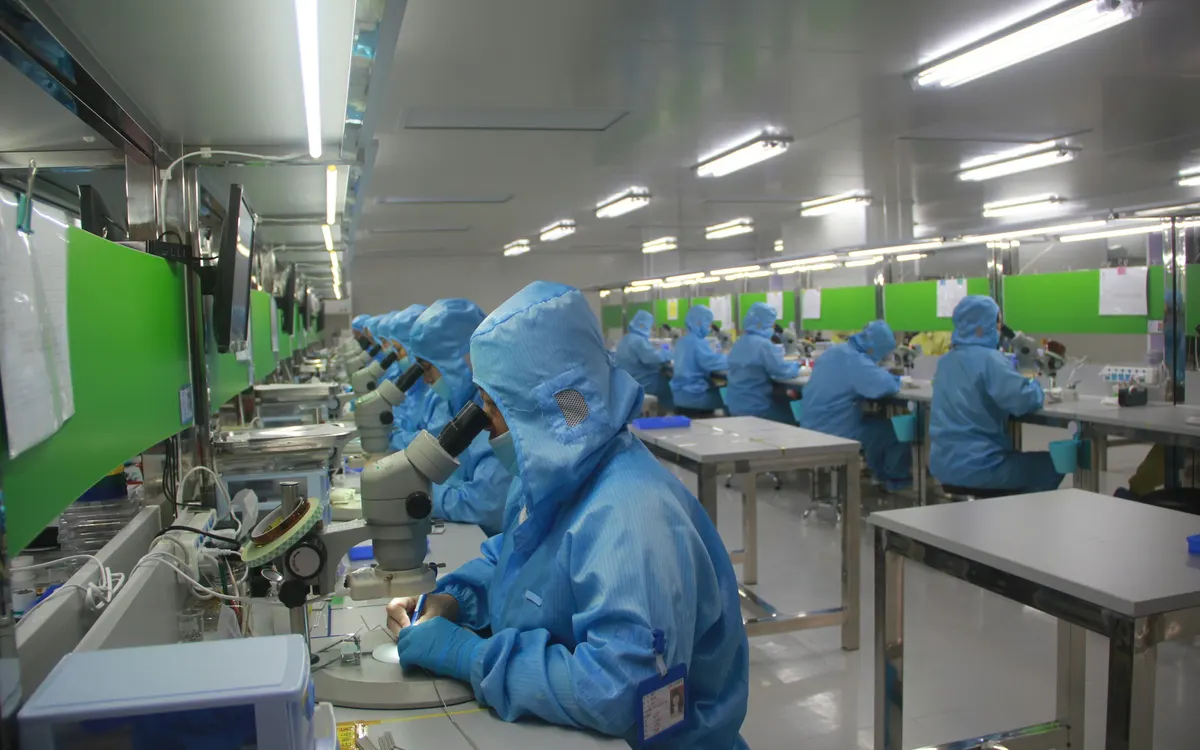 Staff in protective clothing working with microscopes in a cleanroom