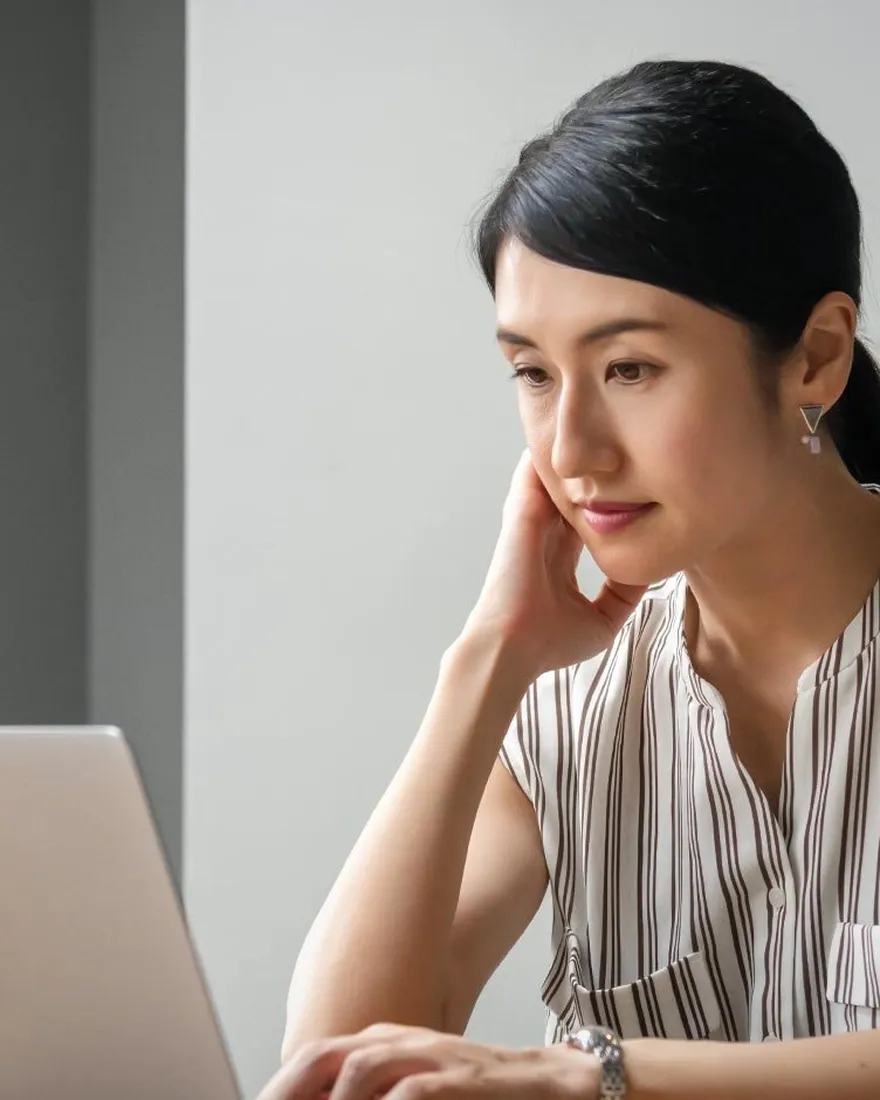 Woman weighing up a choice at a laptop